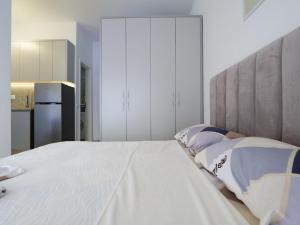 a bedroom with a large white bed and a refrigerator at New and Comfy Studio with Mountain View at 'Mangalem21 Complex' in Tirana