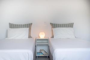 two beds with white sheets and a side table with a lamp at Villa Rodanthi Sivota in Syvota