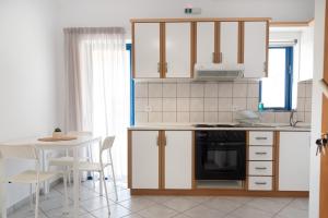 a kitchen with white cabinets and a table with chairs at Villa Rodanthi Sivota in Syvota