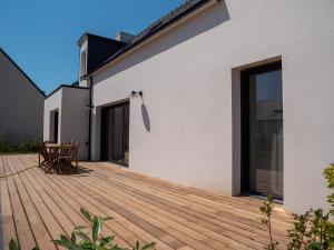 um deque de madeira com uma mesa e cadeiras numa casa em Ker Ouest, Surf House, plage de Pors Carn à pieds em Penmarcʼh