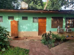 a green house with wooden doors and windows at Alojamiento El Remanso in Puerto Iguazú