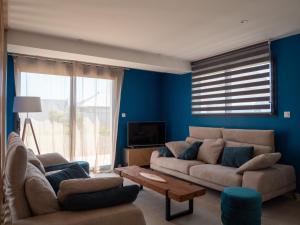 a living room with blue walls and a couch and a table at Ker est, Surf House, plage de Pors Carn à pieds in Penmarcʼh