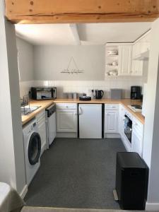 a kitchen with white cabinets and a washer and dryer at The Annexe at Walnut Tree Cottage in Hope under Dinmore