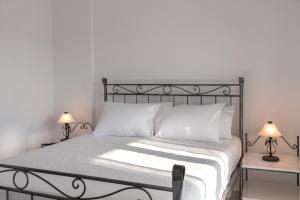 a bedroom with a bed with white sheets and two lamps at Villa Rodanthi Sivota in Syvota