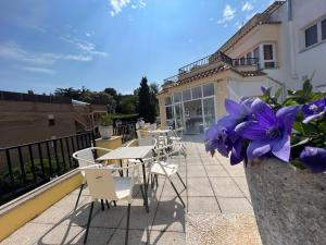 a balcony with tables and chairs and purple flowers at Apartaments Monjardí in Lloret de Mar