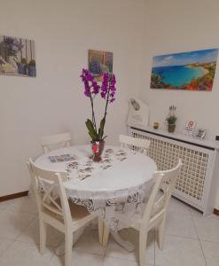 un tavolo bianco con un vaso con fiori viola di LA TERRAZZA DI BASILIO a Olginate