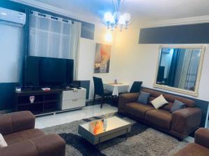 ein Wohnzimmer mit einem Sofa und einem TV in der Unterkunft Appartement luxueux au cœur de la ville in Douala