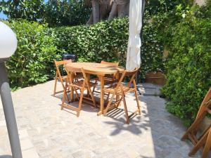 un tavolo in legno con sedie e ombrellone di Residenza Don Camillo a Mondello