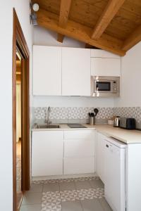cocina blanca con fregadero y microondas en Los Apartamentos del Palacio en Casalarreina