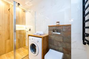 a washing machine in a bathroom with a shower at Apartamenty Usteckie in Ustka