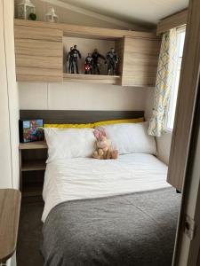 un osito de peluche sentado en una cama en un dormitorio en Beautiful caravan in Trecco Bay! 74 sycomore, en Bridgend