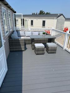 a patio with a couch and a table on a deck at Beautiful caravan in Trecco Bay! 74 sycomore in Bridgend