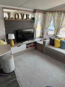ein Wohnzimmer mit einem TV und einem Sofa in der Unterkunft Beautiful caravan in Trecco Bay! 74 sycomore in Bridgend