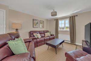 a living room with a leather couch and a tv at The Grange Luxe2 in Ipswich