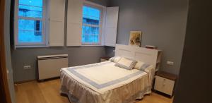 a small bedroom with a bed and two windows at Entre Las Catedrales Campo y Mar 1 y 2 in Lourenzá