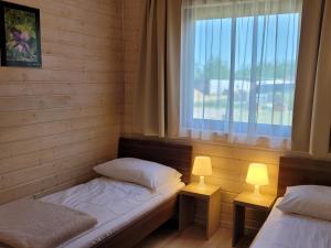 2 camas en una habitación con ventana y 2 lámparas en Kamienny Ogród Holiday Park, en Mikołajki