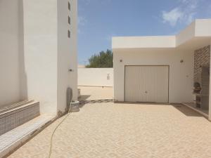 un grande edificio bianco con un grande garage di Villa Château D'eau Djerba a Awlād ‘Umar