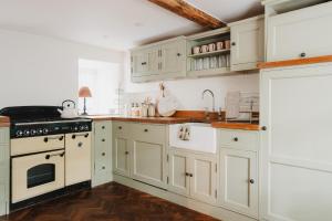 a kitchen with white cabinets and a stove top oven at Lodge Cottage, Castleton in Castleton