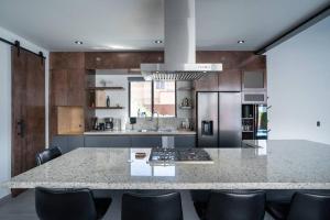 a kitchen with a large marble counter top with black chairs at Casa Alvana in Ensenada