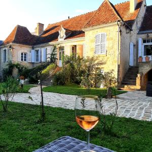 um copo de vinho sentado numa mesa em frente a uma casa em Maison Harmonie em La Châtre