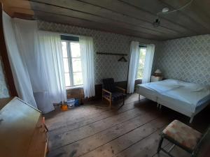 1 dormitorio con 1 cama, 1 silla y ventanas en Frägsta Hälsingegård B&B, en Näsviken