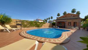 a swimming pool with chairs and a house at Chalet El Parral - Piscina y Sala de Cine in Málaga