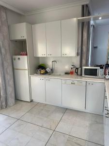 a kitchen with white cabinets and a microwave at Paradiso Kallithea villa in Koskinou