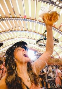 a woman is holding up a glass of beer at AllYouNeed Oktoberfest Basic Camping in Munich