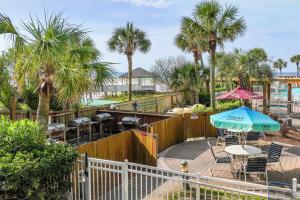 een patio met tafels en stoelen en palmbomen bij The Resorts Of Pelican Beach 1613 Destin (Condo) in Destin