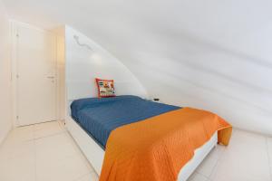 um quarto branco com uma cama com um cobertor laranja em Kisses House - MARINA GRANDE PORT em Procida