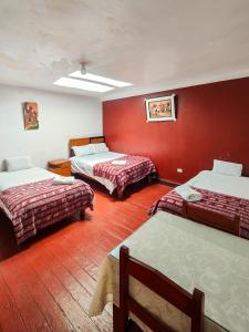 um quarto com duas camas e uma parede vermelha em HOSTAL QORI KANCHA'S INN em Cusco