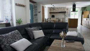 un sofá de cuero negro en una sala de estar con mesa en Le Val Éveillé 4 étoiles - maison de maître de 1773, en Arudy