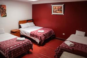 um quarto com duas camas e uma parede vermelha em HOSTAL QORI KANCHA'S INN em Cusco