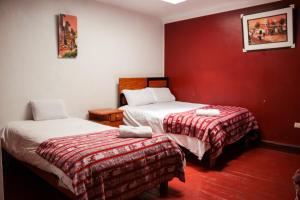 2 letti in una camera con pareti rosse di HOSTAL QORI KANCHA'S INN a Cuzco