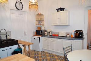 a kitchen with white cabinets and a clock on the wall at Domaine de l'Hyères in Grandcourt