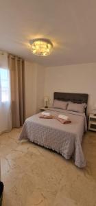 a bedroom with a large white bed with a chandelier at Apartament CALETA in Caleta De Fuste