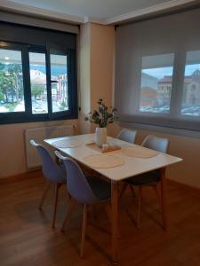 una mesa de comedor con sillas y un jarrón de flores. en Apartamento Aurora en Villaviciosa