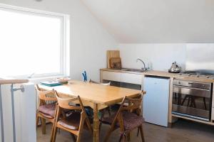 eine Küche mit einem Holztisch und Stühlen in der Unterkunft By the Lighthouse in Vogar