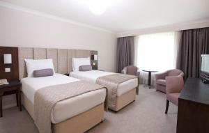 a hotel room with two beds and a television at Sudbury House in Faringdon