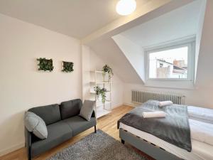 1 dormitorio con cama, sofá y ventana en Jungle Retreat Apartments im Zentrum, en Bremen