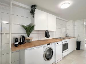 a white kitchen with a washer and a sink at Jungle Retreat Apartments im Zentrum in Bremen