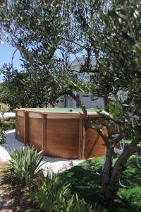 uma banheira de madeira num quintal ao lado de uma árvore em Blue Sky Trogir em Plano