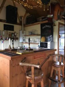 a bar with two wooden stools at a counter at Angies Den - quirky cabin with hot tub & views in Llanasa