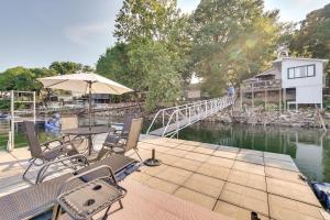 a patio with chairs and an umbrella next to a river at Waterfront Home with Dock in South Grand Lake! in Vinita
