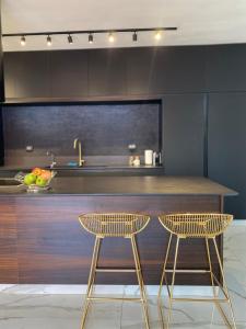 a kitchen with two bar stools and a counter at Boutique Penthouse by Weizmann - פנטהאוס בוטיק in Rechovot