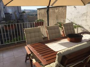 d'une table et de chaises en bois avec un parasol sur le balcon. dans l'établissement Casa Barocco siciliano, à Canicattini Bagni
