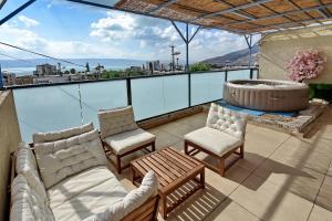 a patio with a hot tub and chairs on a balcony at Levication 2 bedrooms Pool&jacuzzi in Tiberias