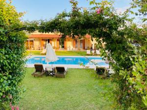einen Garten mit einem Pool mit Stühlen und einem Sonnenschirm in der Unterkunft THE MANSION OF DIONISOS AND DIMITRAS in Linariá