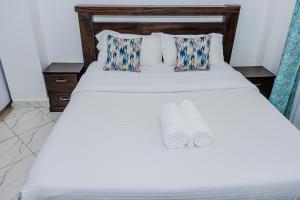 a white bed with two rolled towels on it at Ebony 1bedroom 1033 Nanyuki in Nanyuki
