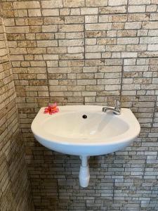 a white sink with a red flower on a brick wall at Anugrah Hotel in Teluk Nara